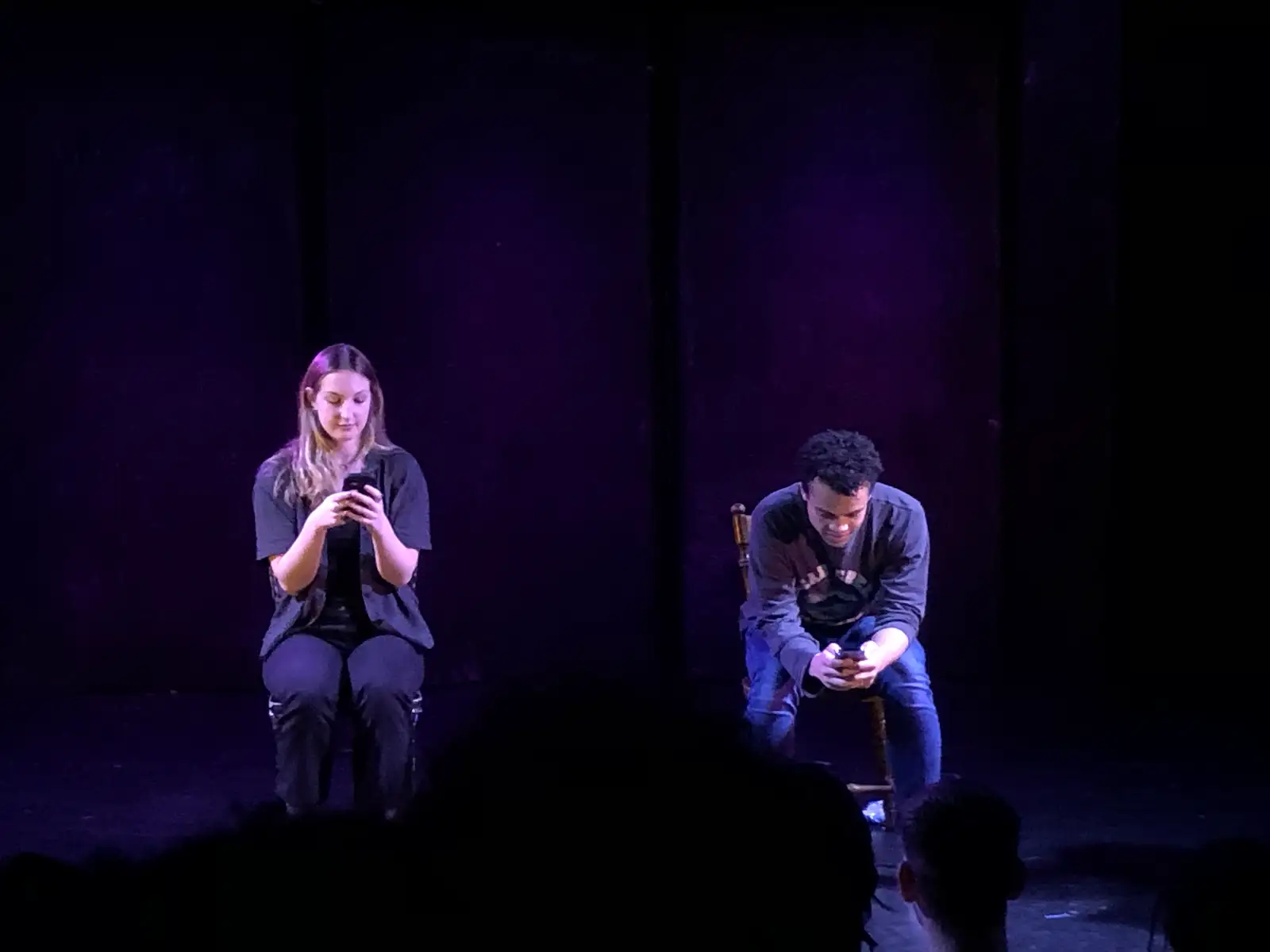 Two characters texting to each other during a performance.